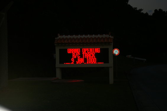 Electronic sign displaying "GRAND OPENING R/C TRACK 9 JAN 1000" with a speed limit sign