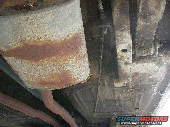 Underside view of a rusty car showing exhaust pipes and muffler
