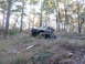 1984 Ford Bronco II - A modified off-road vehicle is parked on a grassy, wooded slope with a tow rope attached.