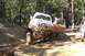1996 Ford Bronco - A mud-splattered off-road truck is shown on a dirt trail with its driver's side door open.