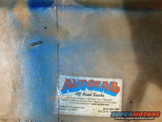 Autofab Off Road Trucks label with address and phone number on a blue and tan textured surface