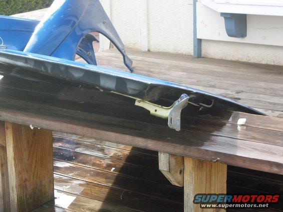 Blue car fender and hood parts resting on a wooden surface