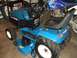 1996 Ford Bronco - A blue Ford tractor is parked indoors, with motorcycles visible in the background.
