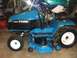 1996 Ford Bronco - A blue Ford L855 tractor is parked indoors, with a dirt bike visible in the background.
