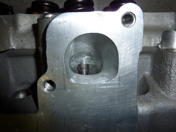 Close-up of an engine cylinder head with a large intake port and a valve stem visible inside