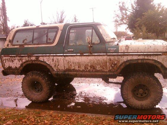 Mud-covered Ford Bronco, likely a 1978 model, parked in puddles