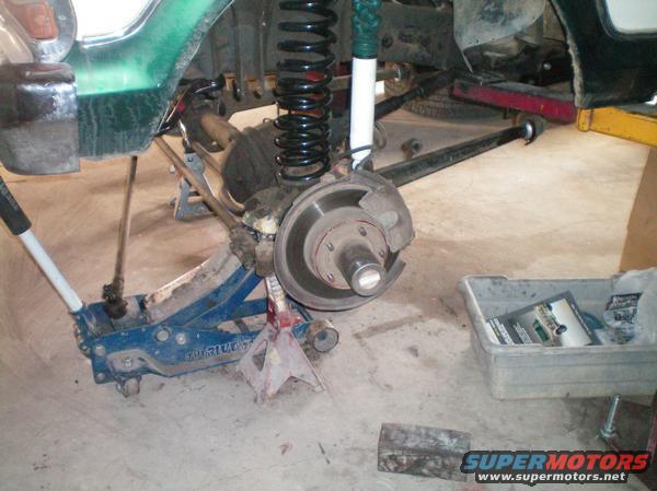 Green 1979 Ford Bronco suspension and brake assembly on jack stands