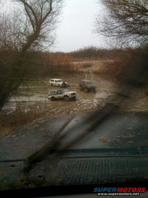 Four-wheel-drive vehicles stuck in mud, one with a visible front end