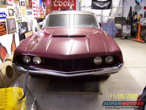 maroon car front end with dual headlights and chrome bumper