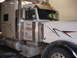 2003 Peterbilt 379 - Close-up of a white semi-truck's cab, showing custom decals and chrome detailing.