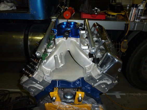 V8 engine part with aluminum intake manifold, blue painted mounts, and chrome valve covers