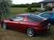 1993 Mazda MX-3 - A red 1993 Mazda MX-3 is parked on a lawn with a blue car in the background.