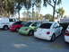 2003 Volkswagen Beetle - Three Volkswagen Beetles, a red convertible, a green coupe, and a white coupe, are parked next to a white van.