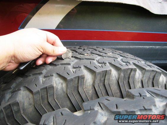 hand holding coin to check tire tread depth