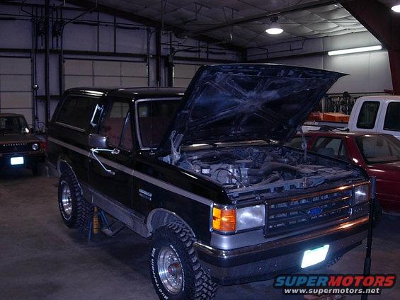 1989 Ford Bronco with hood open in garage, another vehicle in background