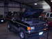 1989 Ford Bronco - 1989 Ford Bronco in a garage with its hood up, showing the engine bay.