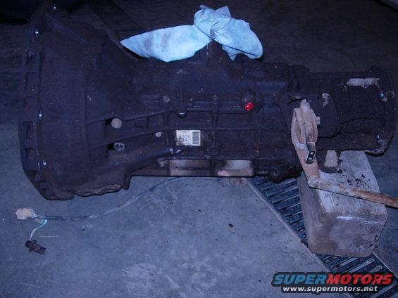 Automatic transmission resting on blocks, blue shop towel on top. Part number label visible