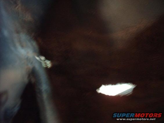 Car interior with dark brown headliner, a hole letting in light, and a blurry blue door panel