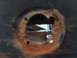 1978 Ford Mustang II - A close-up view of a rusted hole on the underside of a vehicle, revealing internal structural components.