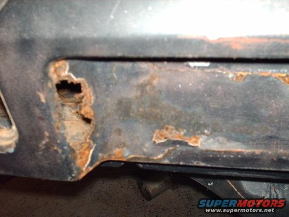 Close-up of rusted car panel with hole