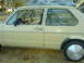 1983 Volkswagen Rabbit - Side view of a tan 1983 Volkswagen Rabbit, showing the interior roll cage and a car cover on the roof.