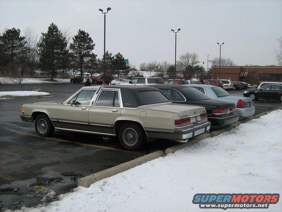 Rear view of a tan and black 1988 Mercury Grand Marquis parked in a snowy lot