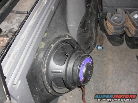 Speaker mounted in car interior panel, with boots visible in background
