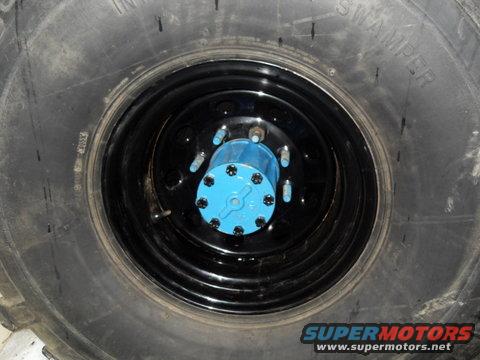 Close-up of a large tire with a blue wheel hub and black rim
