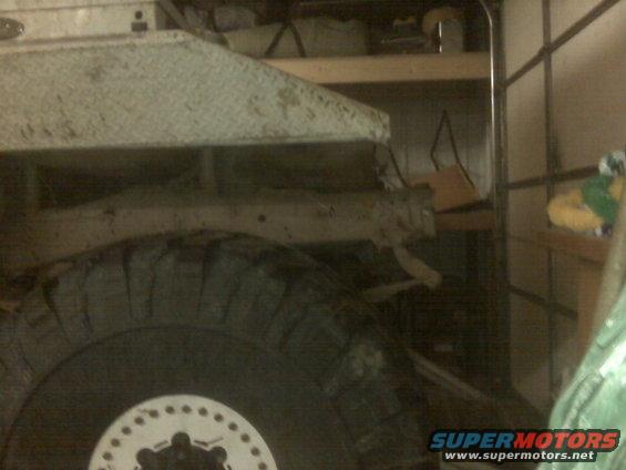 Truck frame and large tire with white hub. Interior garage setting