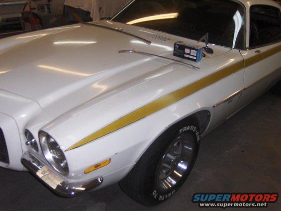 White Chevrolet with gold stripe down the side, showing the front fender and hood. A box and some trim pieces are on the hood