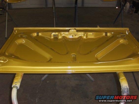 Gold painted car hood underside with bracing and latch mechanism, resting on sawhorses