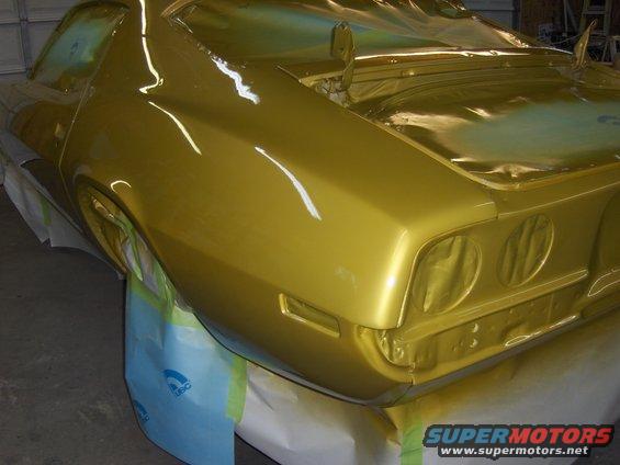 Gold 1970 Chevrolet Camaro rear quarter panel covered in masking tape and plastic during paint job