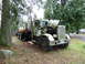 1981 Kenworth W900A - A weathered green truck sits abandoned with its hood open, surrounded by trees and grass.
