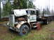 1981 Kenworth W900A - This white Peterbilt 359 logging truck, with its hood open, reveals the engine and is parked outdoors.