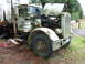1981 Kenworth W900A - This weathered Peterbilt truck sits in a grassy area, its hood raised to reveal the engine compartment.