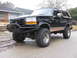 1994 Ford Bronco - This lifted black Ford Bronco features a custom front bumper and tan body trim.