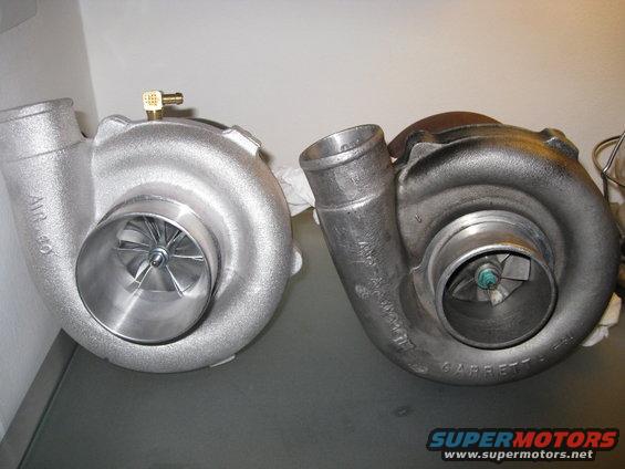 Two turbochargers side-by-side on a gray surface. The left turbo is clean and silver, the right is darker and appears used. Text 'AIR 40' is visible on the left turbo