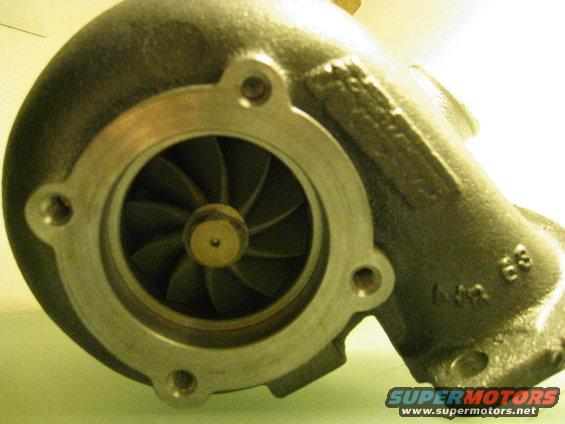 Turbocharger compressor housing with visible impeller blades and mounting holes. Part numbers are stamped on the housing