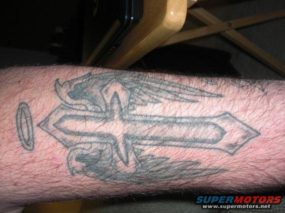 tattoo of a cross with wings and a halo on an arm