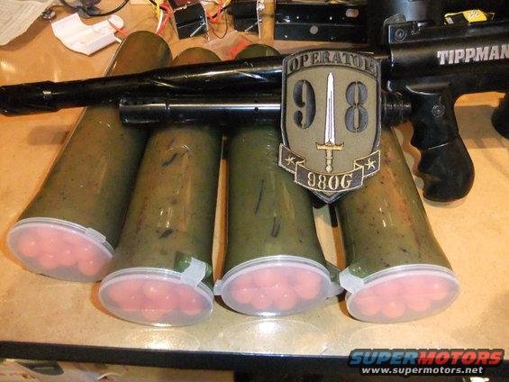 Tippmann paintball gun with four loaded hoppers and an Operator 98G patch