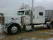 2003 Peterbilt 379 - This 2003 Peterbilt 379 semi-truck is parked outside a large white structure, possibly a barn or warehouse.