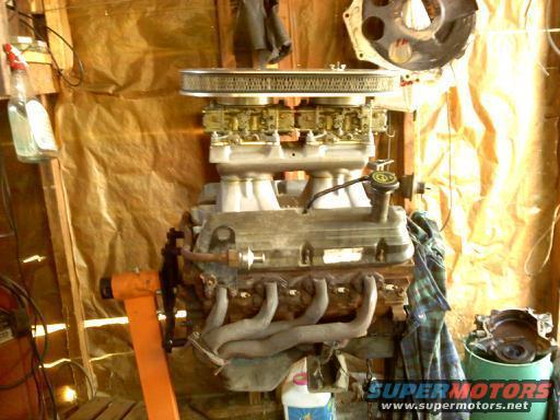 Engine on an orange stand, with a carburetor and air cleaner assembly