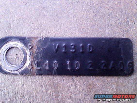 Close-up of a black metal tag with stamped numbers and letters, showing V1310 and L10 10 2 2A06