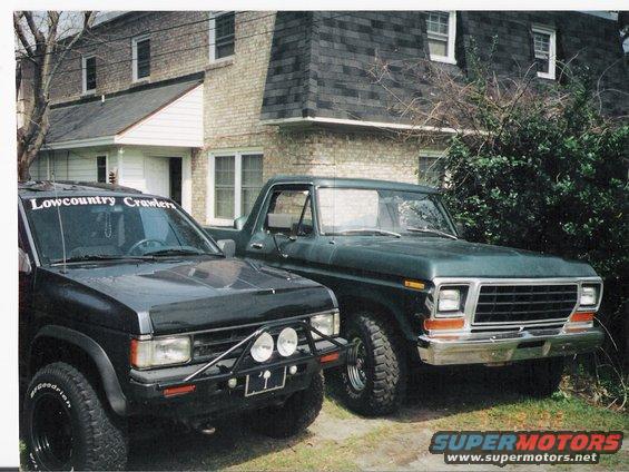 Green 1979 Ford Bronco front 3/4 view with black SUV