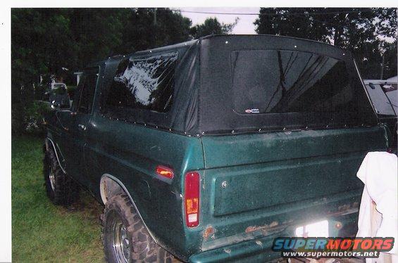 Green 1978 Ford Bronco rear view with black soft top and large tires