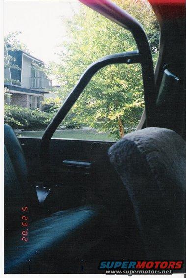 Interior shot looking out passenger window, shows seat, roll bar, and trees outside