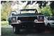 1979 Ford Bronco - This green SUV, possibly a 1979 Ford Bronco, is parked outside with its door ajar. Another vehicle is visible to the right.