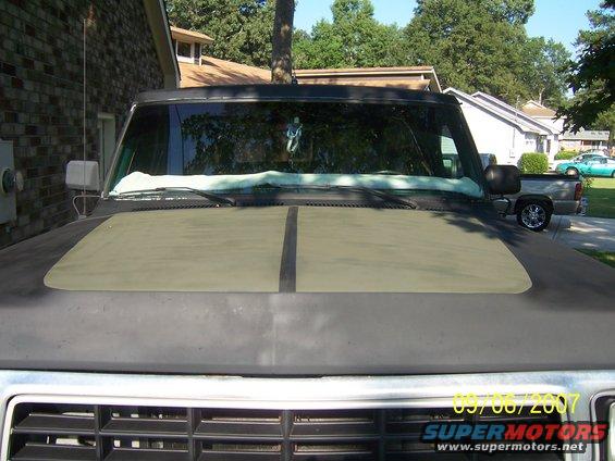 Dark SUV hood with olive green panel. Another truck visible