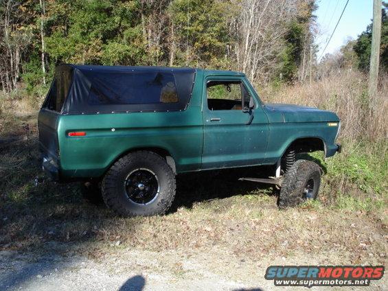 Green 1979 Ford Bronco side view with black soft top and lifted suspension