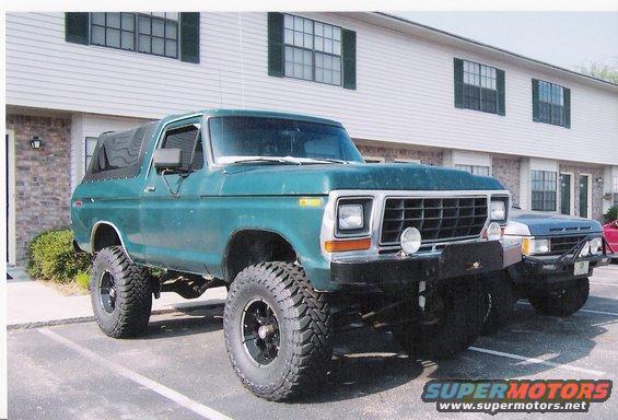 Green 1979 Ford Bronco with lifted suspension and large tires parked next to another vehicle